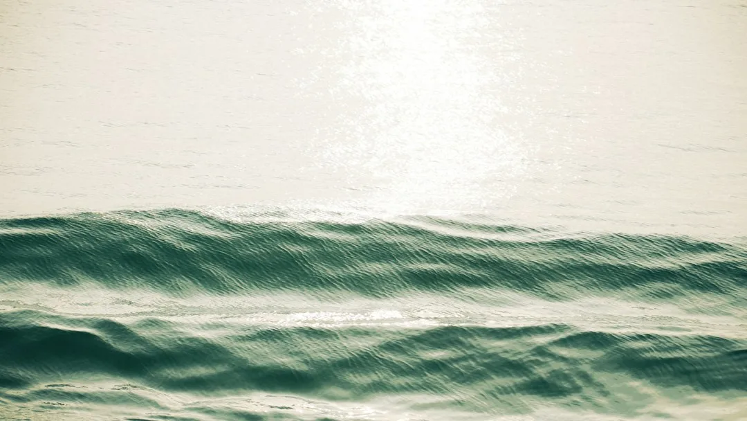 Layered ocean waves reflecting warm sunlight, suggesting shifting perspectives.